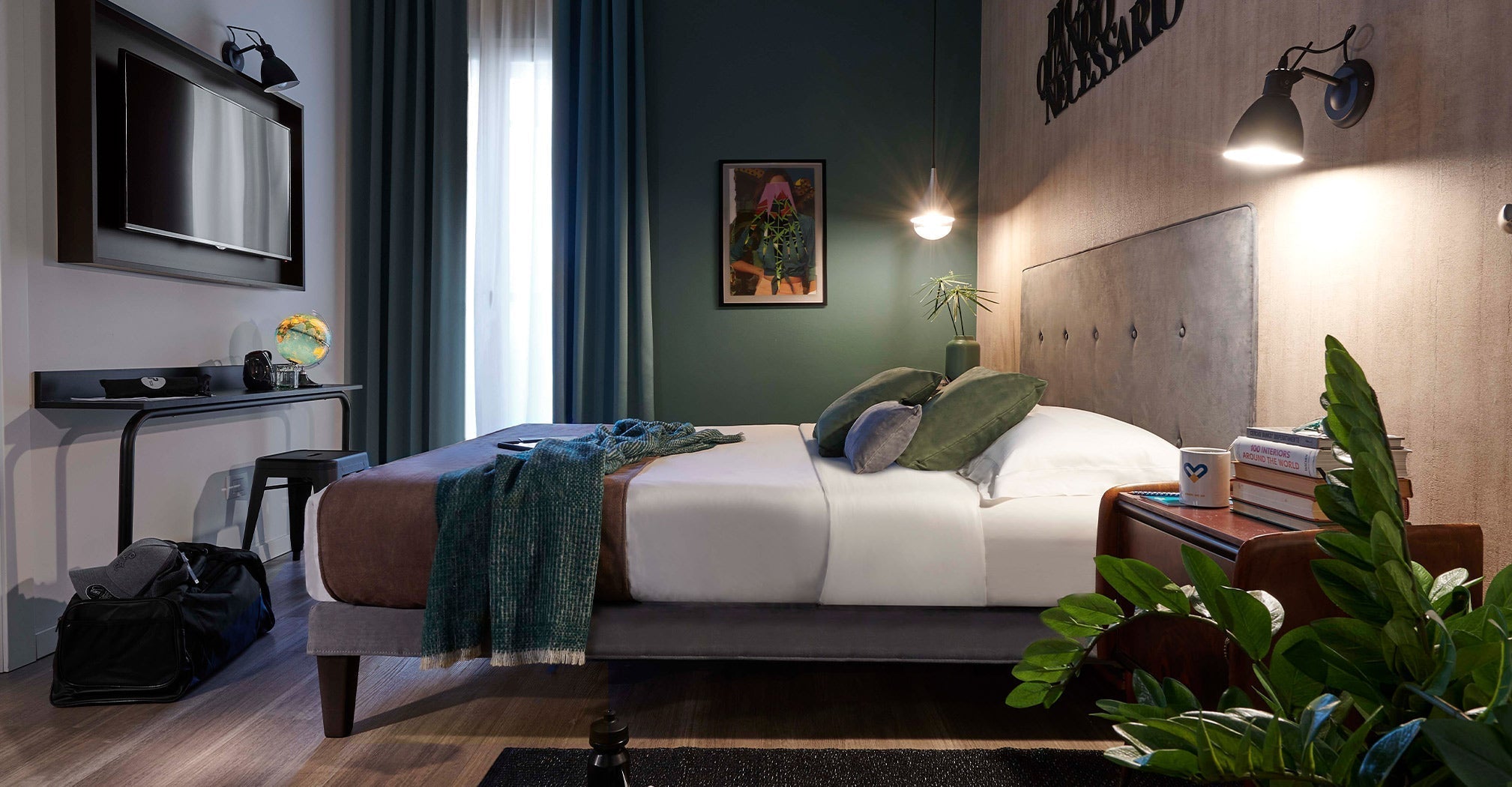 A hotel room featuring a luxurious bed, a desk, and decorative plants, designed for comfort and relaxation.
