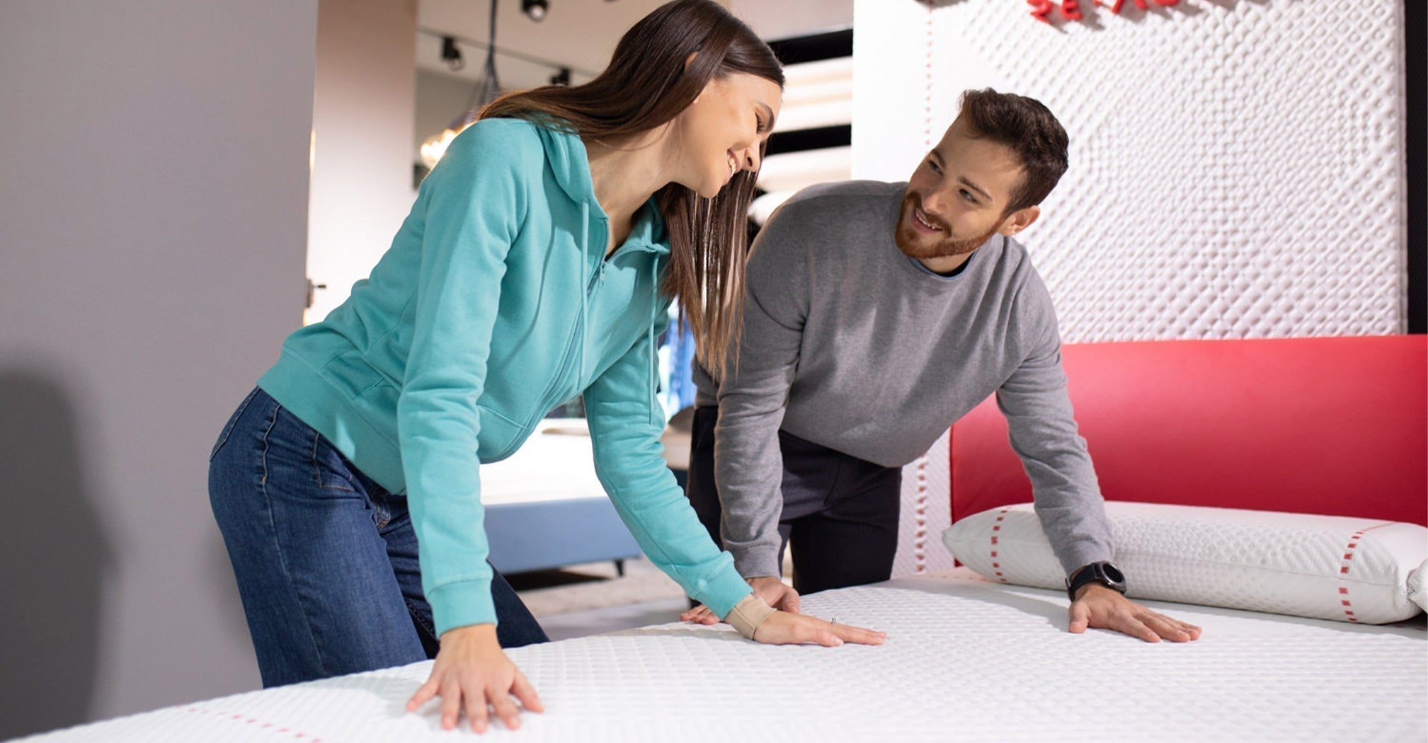 A man and woman examine a mattress, reflecting Miami's growing interest in European mattress styles.